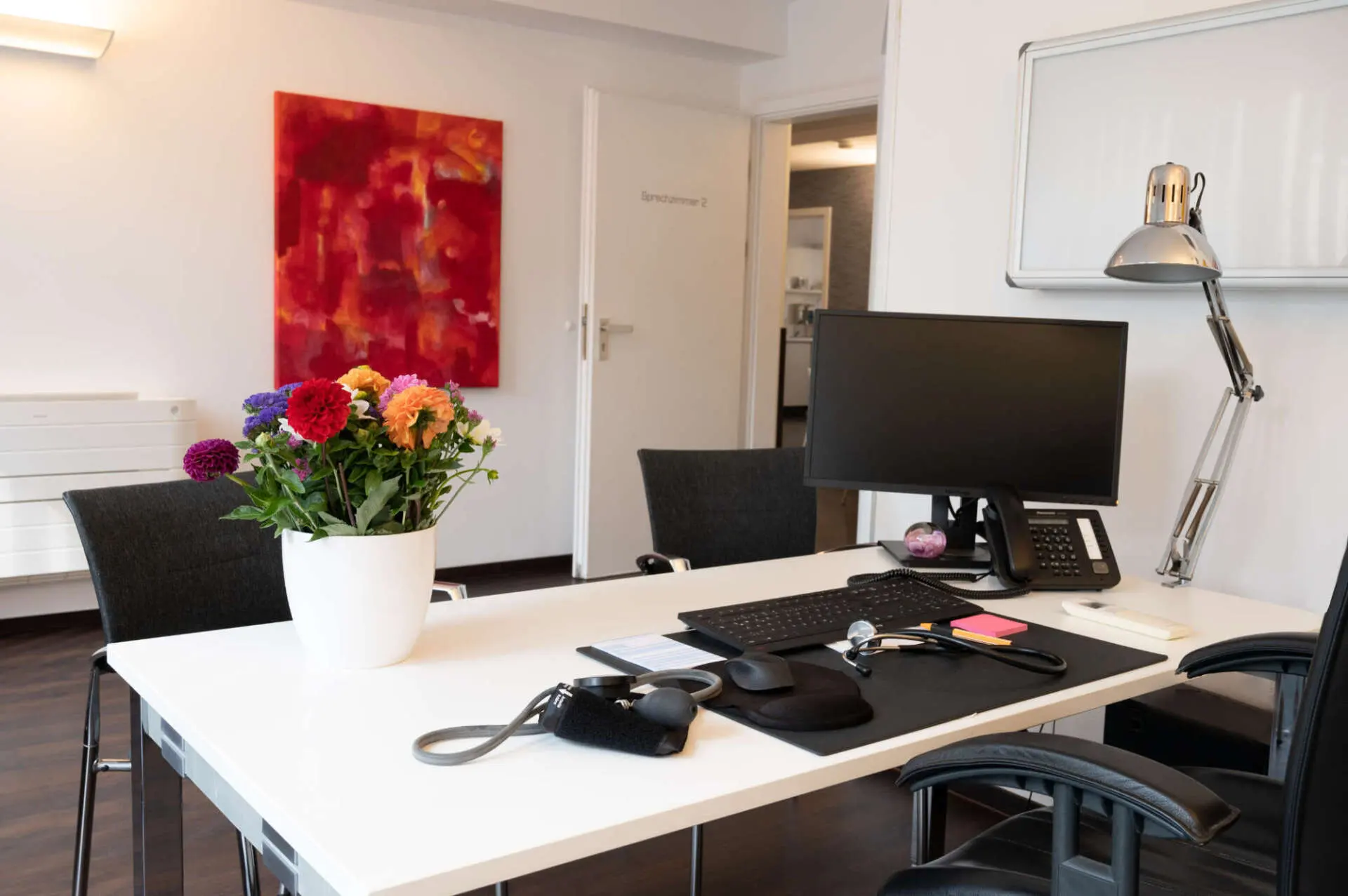 Sprechzimmer mit Schreibtisch und Blumenstrauß